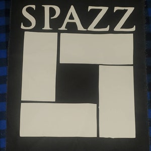 May include: Black fabric patch with white lettering that reads "Spazz" and a white geometric design.