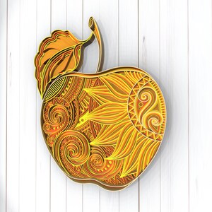 May include: A decorative apple with a detailed, intricate design in shades of orange and yellow. The apple is made of paper and has a 3D effect.