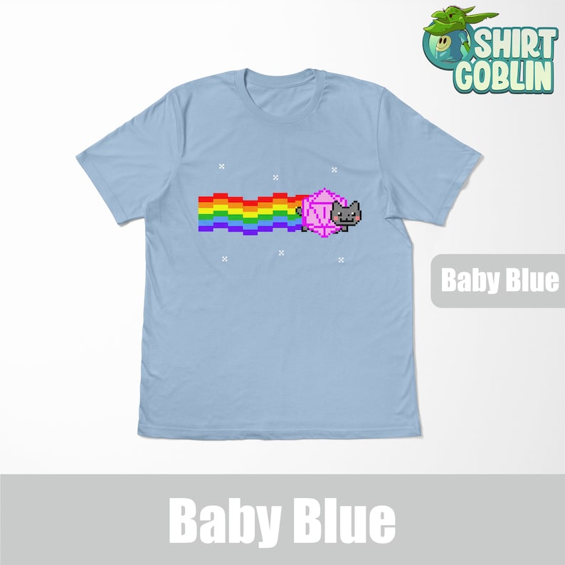 May include: A baby blue t-shirt with a pixelated rainbow and a cat wearing a pink dice. The text "Shirt Goblin" is in the top right corner of the image. The text "Baby Blue" is in the bottom right corner of the image.