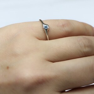 May include: A silver ring with a light blue gemstone set in the center.