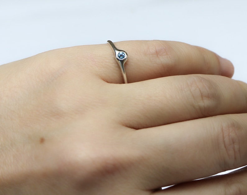May include: A silver ring with a light blue gemstone set in the center.