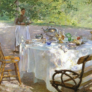 May include: A white tablecloth covers a table set for an outdoor tea party. A silver teapot, teacups, and a plate of pastries are arranged on the table. A woman in a white apron stands behind the table, holding a tray with a teapot and cups. The scene is set in a lush green garden with trees and foliage in the background.