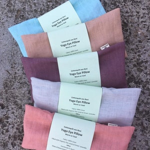 Puede incluir: Cinco almohadas para los ojos de yoga en diferentes colores, incluyendo azul claro, beige, morado, gris y rosa. Cada almohada está hecha de lino y rellena de semillas de lino y lavanda seca. Las almohadas están hechas a mano en Berlín y están disponibles para comprar en Instagram.