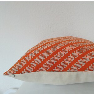 May include: Orange and white patterned cushion with a white border. The cushion is made of a soft, comfortable fabric and has a subtle sheen.