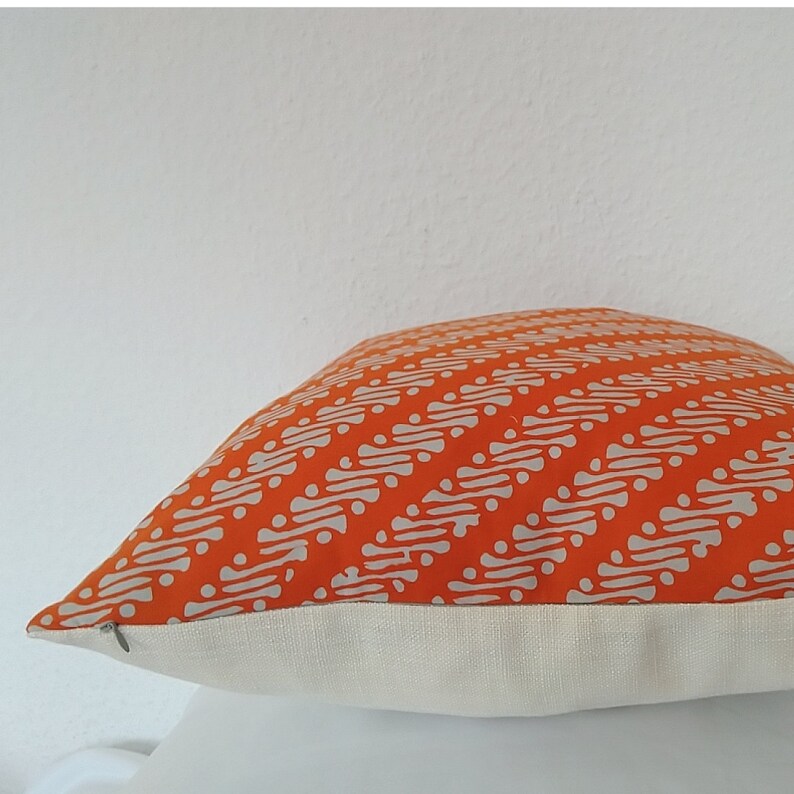 May include: Orange and white patterned cushion with a white border. The cushion is made of a soft, comfortable fabric and has a subtle sheen.