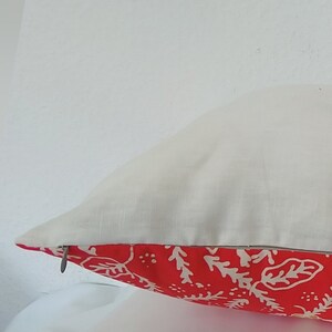 Pu&ograve; includere: Un cuscino rosso e bianco con motivo e chiusura a zip. Il cuscino &egrave; realizzato in un tessuto bianco morbido e presenta un motivo floreale rosso e bianco.