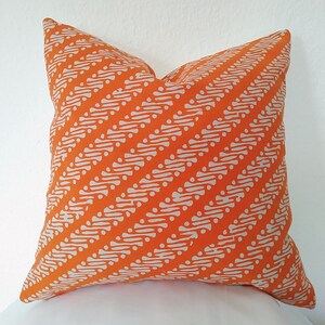 May include: Orange cushion with a white geometric pattern. The pattern is a series of diagonal lines with small white circles.