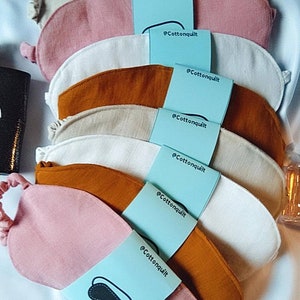Könnte beinhalten: Ein Stapel von acht Augenmasken in verschiedenen Farben, darunter Beige, Rosa, Weiß und Braun. Jede Maske ist mit dem Text "@Cottonquilt" gekennzeichnet.