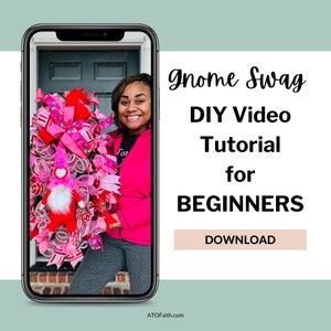 以下が含まれることがあります： 女性がピンクと赤のバレンタインデーのノームリースを持っています。リースはハート、リボン、その他の華やかな装飾で飾られています。テキスト「Gnome Swag DIY Video Tutorial for BEGINNERS DOWNLOAD」は白い背景に表示されています。