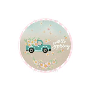 May include: Round design with a teal truck carrying flowers, the words "Hello Spring", and butterflies. The background has a light blue and tan color scheme with a pink border. Spring-themed design.