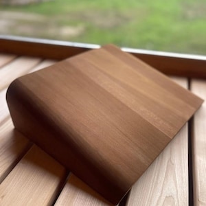 Può includere: Tagliere rettangolare in legno con bordo curvo. Il tagliere è realizzato in legno marrone chiaro e ha una superficie liscia e lucida. Il tagliere è nuovo.