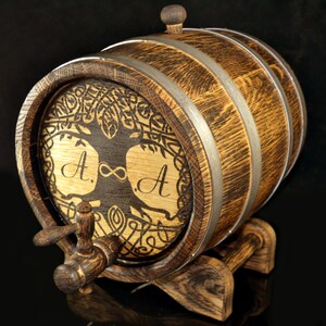 May include: A wooden barrel with a tree of life design and the initials "A. &infin; A." engraved on the front. The barrel has a metal tap and sits on a wooden stand.