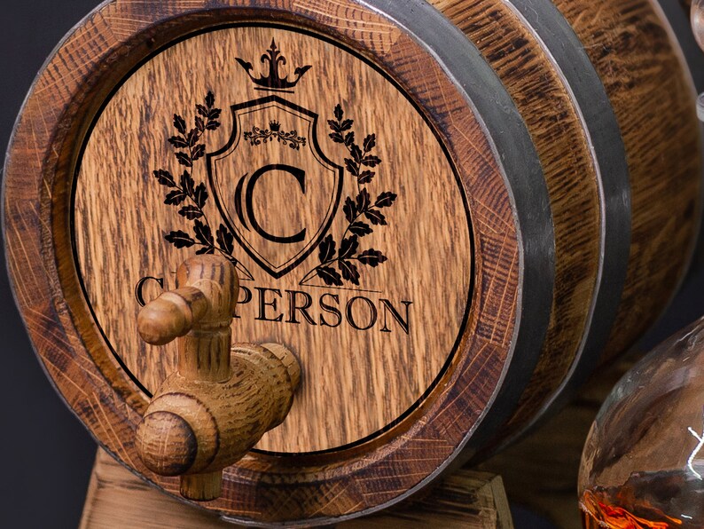 May include: A wooden barrel with a spigot and a personalized inscription. The inscription includes a crown, a shield with the letter "C", and the name "C. PERSON".