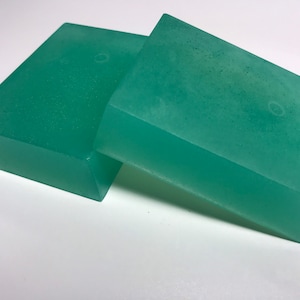 May include: Two translucent green bars of soap, stacked on top of each other.