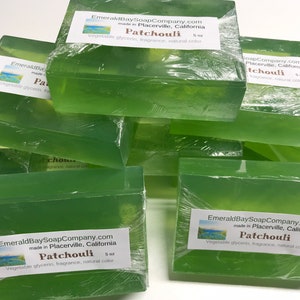 May include: A stack of clear green soap bars with a label that reads "Emerald Bay Soap Company.com made in Placerville, California Patchouli 5 oz Vegetable glycerin, fragrance, natural color".