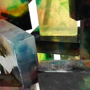 May include: A stack of colorful, translucent blocks with abstract patterns. The blocks are made of resin and have a variety of colors, including green, blue, red, and yellow.