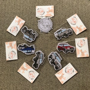 May include: Eight car air fresheners with a nature-inspired design. Each air freshener features a cartoon illustration of a vehicle with a roof rack and a mountain range in the background. The text "Gone Exploring" and "Car Air Freshener" are printed on each air freshener.
