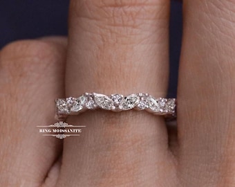 May include: A close-up of a silver ring with multiple marquise-cut and round-cut gemstones. The ring is set with a continuous row of stones. The text "RING MOISSANITE" is visible at the bottom of the image.
