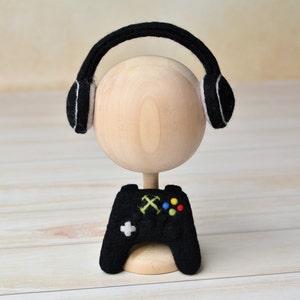 May include: A wooden doll head with black felt headphones and a black felt video game controller.