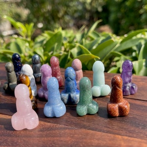 Könnte beinhalten: Eine Sammlung von 15 kleinen, geschnitzten Kristallfiguren in verschiedenen Farben, darunter rosa, blau, grün, braun, lila und weiß. Die Figuren sind auf einer Holzoberfläche angeordnet.