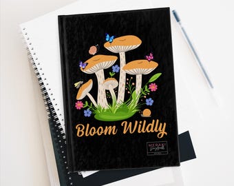 May include: Black journal with a mushroom illustration and the text "Bloom Wildly". The mushrooms are orange and white with green leaves and flowers. The journal has a black background with a white logo that says "Meraki Journals".