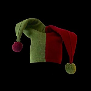 May include: A green and red jester hat with a pom-pom on each end.
