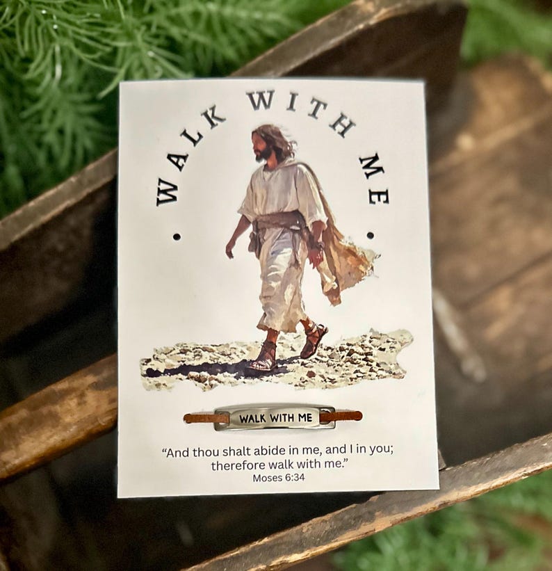 May include: A white card with the words "WALK WITH ME" arched above an image of a figure in white robes. Below, a small metal bar reads "WALK WITH ME". The card includes a quote from Moses 6:34.