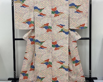 Könnte beinhalten: Ein Kimono mit einem sich wiederholenden Muster aus stilisierten Wellen in Creme, Rot, Blau und Grün. Das Kleidungsstück hat weite Ärmel und einen langen Schnitt und wird auf einem schwarzen Ständer präsentiert. Das Muster bedeckt den Stoff.