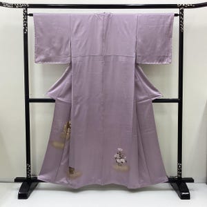 Könnte beinhalten: Ein helllavendelfarbener Kimono mit weiten Ärmeln und geradem Schnitt. Das Kleidungsstück ist mit kleinen, zarten Blumenmotiven in Weiß- und hellen Brauntönen verziert, die sich nahe am unteren Saum auf dem glatten, einfarbigen Stoff befinden.