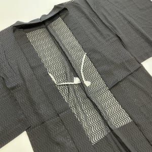 May include: Dark gray kimono with a wave pattern. The kimono features a white wave pattern down the front and a white tie closure. The sleeves are long and the fabric appears to be lightweight.