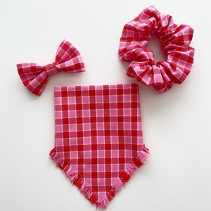 May include: A set of three pink and red gingham accessories: a bow tie, a scrunchie, and a bandana with frayed edges.