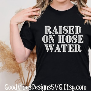 May include: Black t-shirt with white text that reads "RAISED ON HOSE WATER".