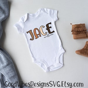 Puede incluir: Un body blanco para beb&eacute; con el nombre "Jace William" escrito en letras marrones, naranjas y beige.