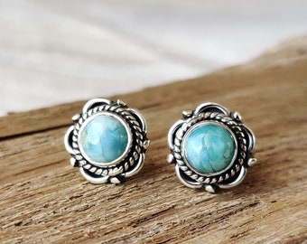May include: A pair of silver earrings with a blue gemstone set in a decorative silver frame.