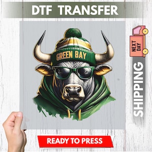 May include: DTF transfer of a bull wearing a green and yellow beanie with "GREEN BAY" text, green sunglasses, and a green hoodie. The image is on a light grey background with "READY TO PRESS" text at the bottom.