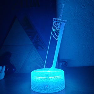 May include: A blue light-up lamp shaped like a sword with a textured base.