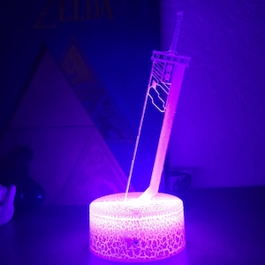 May include: A purple and white 3D printed lamp shaped like a sword. The lamp is on a textured base and is lit up.