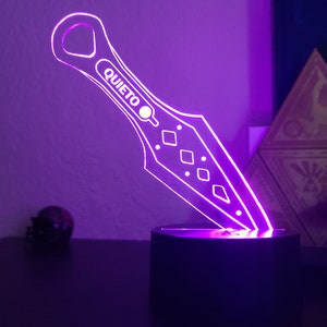 May include: A purple LED light shaped like a throwing knife with the word "QUIETO" on the blade.