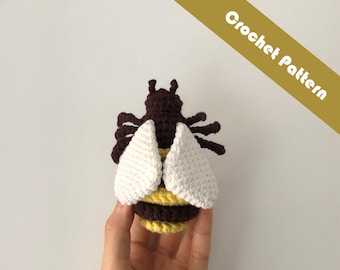May include: A crocheted bee toy with brown and yellow stripes, white wings, and black antennae.