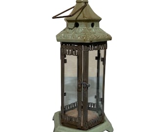 Farol de jardín vintage de metal y cristal color verde óxido con aspecto desgastado.