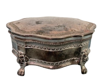 Joyero antiguo chapado en plata con adornos, patas de garra de león y forro de terciopelo azul.