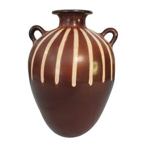 Puede incluir: Un jarrón de cerámica marrón con dos asas y una base ancha. El jarrón presenta rayas verticales de color crema sobre un fondo marrón oscuro. El borde y las asas son de un tono marrón más oscuro.