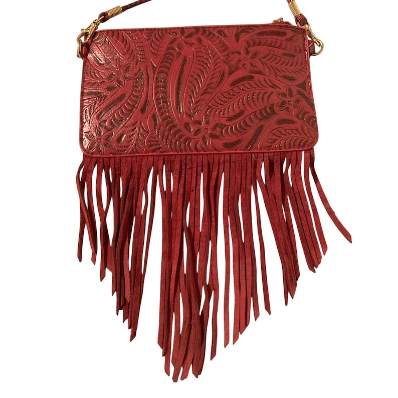 Puede incluir: Un bolso bandolera rojo con un dise&ntilde;o floral en relieve y largas flecos. El bolso tiene una correa de cadena dorada y un cierre de cremallera. El bolso est&aacute; hecho de un material similar al cuero.