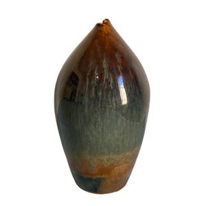 May include: A teardrop-shaped ceramic vase with a glossy finish. The glaze features a gradient of colors, transitioning from a deep brown at the pointed top to a muted sage green in the center, and ending with a warm amber and dark blue base.