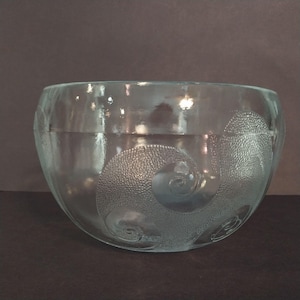 May include: A clear glass bowl featuring a rounded shape and a wide opening. The exterior surface is decorated with etched, textured spiral patterns that have a stippled appearance, creating a contrast against the smooth, transparent glass body.