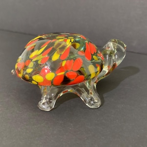 May include: A white ceramic mug with a black handle and the text "But First, Coffee" in a bold, black font. The mug is set against a neutral background, highlighting its simple design.