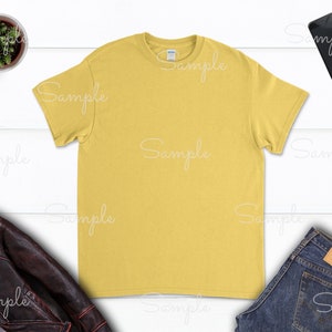 May include: A plain yellow t-shirt with a crew neck. The t-shirt is laying flat on a white surface.