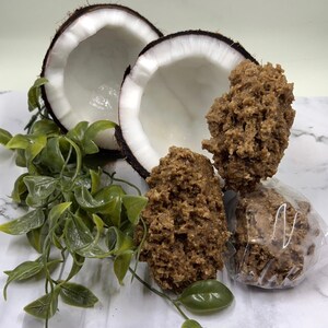 May include: Two halves of a coconut shell with brown coconut candy inside. The candy is in various shapes and sizes, some are wrapped in clear plastic.