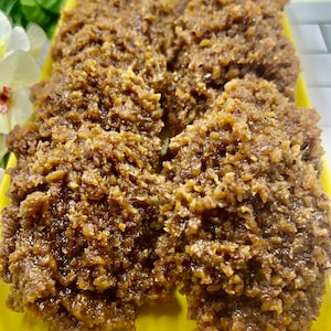 May include: Close-up of a plate of brown coconut candy. The candy is arranged in a cluster on a yellow plate.