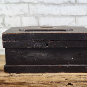 May include: A dark wooden box with a hinged lid and a small metal latch. The box is made of wood and has a dark brown finish.